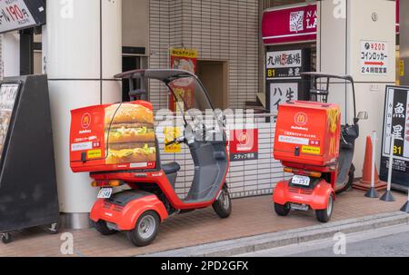 Ein Seitenbild von zwei 3-rädrigen Liefermotorrädern von McDonald's mit Dächern und einem Aufbewahrungsbehälter hinten mit Bildern von Pommes Frites und einem Hamburger. Stockfoto