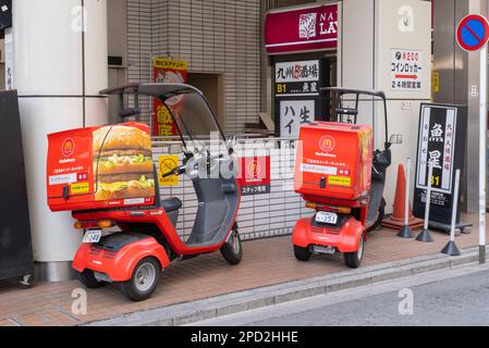 Ein Seitenbild von zwei 3-rädrigen Liefermotorrädern von McDonald's mit Dächern und einem Aufbewahrungsbehälter hinten mit Bildern von Pommes Frites und einem Hamburger. Stockfoto