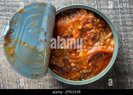Offene Sardinen in Tomatensoße auf Holzhintergrund, aus nächster Nähe, Draufsicht Stockfoto