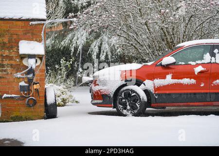 Ladestation für Elektroautos in ländlichen Gebieten lädt ein vollelektrisches Auto, Stadtleben, mit Schnee bedeckt Stockfoto