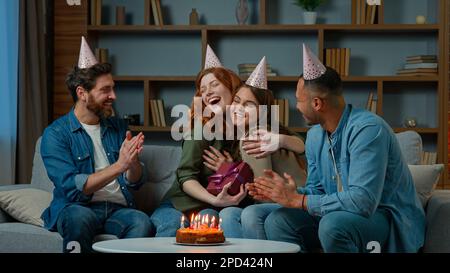 Aufgeregte Frau erhält Geschenk von Freunden vielfältige Kollegen aus verschiedenen Rassen gratulieren Happy Birthday präsentieren Überraschung Box. Ethnische Frauen Stockfoto