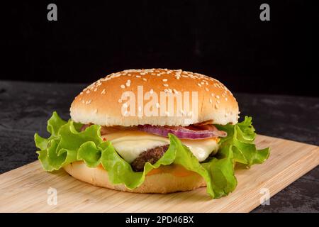 Burger mit Rinderpastete auf einem Holzteller auf dunklem Hintergrund Stockfoto