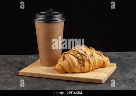 Pappbecher mit duftendem Kaffee und Croissants auf dunklem Hintergrund. Layout für Design Stockfoto