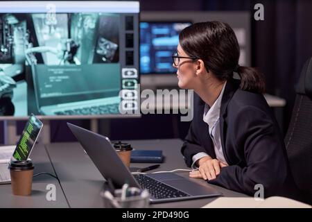 Seitliches Porträt einer seriösen Geschäftsfrau, die sich die Aufnahmen der Überwachungskamera ansieht Stockfoto