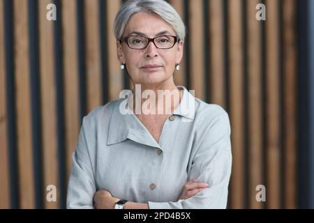 Schöne reife Frau im Büro Arme gekreuzt Stockfoto