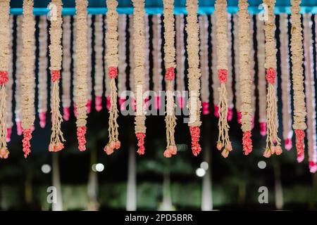 Ein lebendiges Schauspiel aus farbenfrohen Girlanden und Blumen, die an der Decke eines Hochzeitsempfangs im Freien hängen Stockfoto