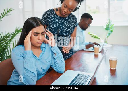 Die junge Frau sieht gestresst aus, während ihr Vorgesetzter im Callcenter nachsieht Stockfoto
