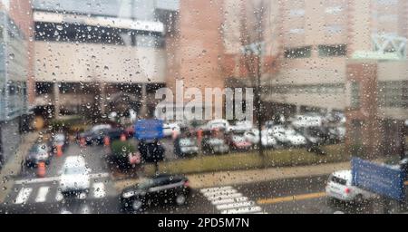 Nahaufnahme von Regentropfen an einem Fenster mit einem sanft verschwommenen Stadtbild dahinter. Atmosphärischer Hintergrund für regnerische Tage, der Stimmung, Wetter, Ruhe und s vermittelt Stockfoto