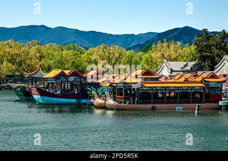 Zwei Drachenboote mit bronzefarbenen, schwarz-weiß gemusterten Hüllen, die am Kunming-See an der Seite von zwei Junk-Booten vertäut sind, alle mit Holzpavillons ausgestattet Stockfoto