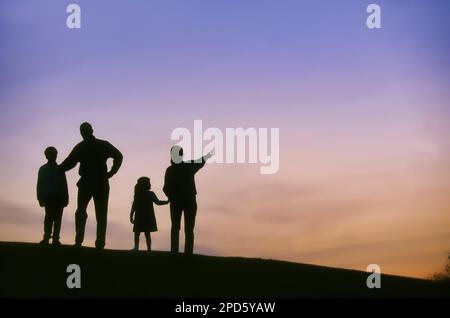 Silhouette Liebe der Familie Mutter Vater und zwei Kinder schauen und tragen zum Sonnenuntergang bei Stockfoto