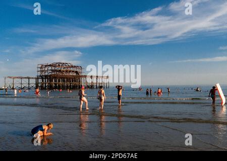 Leute, die die Ebbe am West Pier am Brighton Beach genießen - Brighton & Hove, East Sussex, Großbritannien Stockfoto