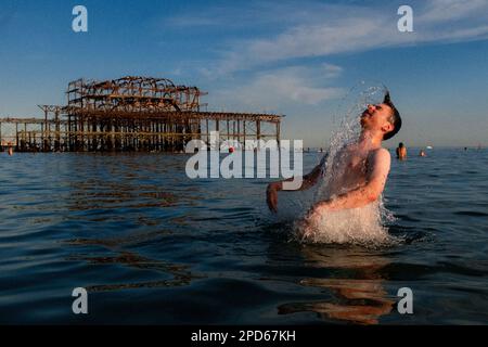Leute, die die Ebbe am West Pier am Brighton Beach genießen - Brighton & Hove, East Sussex, Großbritannien Stockfoto