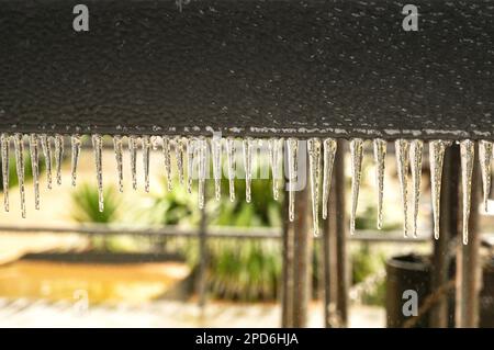 Eiszapfen auf dem Boden eines Metallschilds nach extremen Wetterbedingungen und eiskaltem Regen. Keine Menschen. Stockfoto