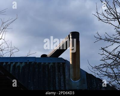 Ein alter rostiger Metallschornstein, der auf einem Dach zerbrochen ist. Nahaufnahme Stockfoto