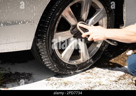 Zwei Masern reinigen einen silbernen Auto-Sprühschaum mit einem Hochdruckreiniger ein Auto waschen Stockfoto