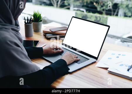 Eine wunderschöne muslimische Frau benutzt einen weißen Computerbildschirm, der Text und Illustrationen auf leeren Flächen ablegt Stockfoto