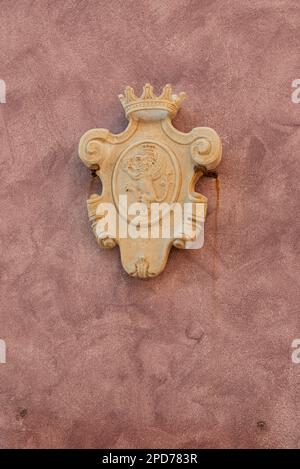 Wand in venezianischem Rot mit einem geschnitzten Wappen aus Sandstein, Rovinj, Kroatien Stockfoto