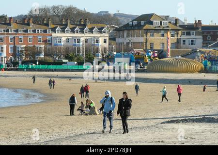 Weymouth, Dorset, Großbritannien. 14. März 2023 Wetter in Großbritannien. Spaziergänger am Strand genießen den warmen Frühlingssonnenschein am Nachmittag in Weymouth in Dorset. Bildnachweis: Graham Hunt/Alamy Live News Stockfoto