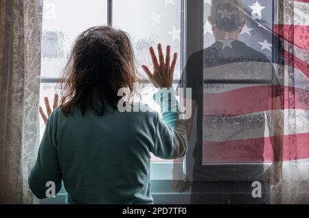 Eine Frau, die an Regentagen aus dem Fenster schaut. Mann mit geballten Fäusten. Häusliche Gewalt, Gewalt, gewalttätiger Partner, Menschenhandel, Sklaverei, Psychische Gesundheit... Stockfoto