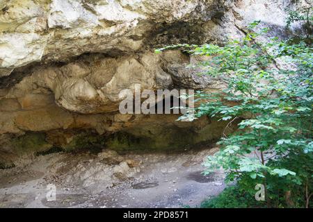 Eintritt in eine Karsthöhle natürlichen Ursprungs. Die Höhle wurde natürlich im Fels gebildet, Kondensat bildet sich am Eingang aufgrund der Temperatur Stockfoto