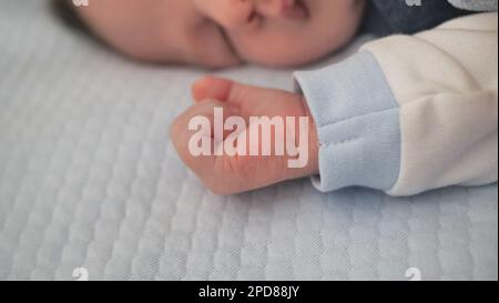 Die Hand des Babys über die blaue Decke. Sentimentaler Moment mit einem ruhenden Kleinkind. Winzige Hand eines neugeborenen Sohnes. - Das Baby Stockfoto