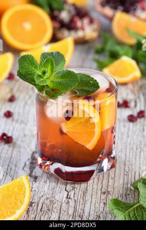 Der Cocktail wird aus Granatapfel und Orangensaft mit Tequila oder Gin mit Tonic hergestellt. Serviert in einem Glas mit Eis, orangefarbene Scheiben mit Stockfoto