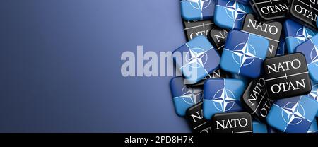 Logos der NATO-Nordatlantikvertrags-Organisation eine militärische Allianz auf einem Haufen auf einem Tisch. Speicherplatz kopieren. Webbannerformat. Stockfoto