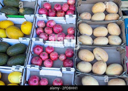 Verschiedene Melonen- und Granatäpfel-Sorten in einer Schachtel, die auf dem Markt verkauft werden Stockfoto