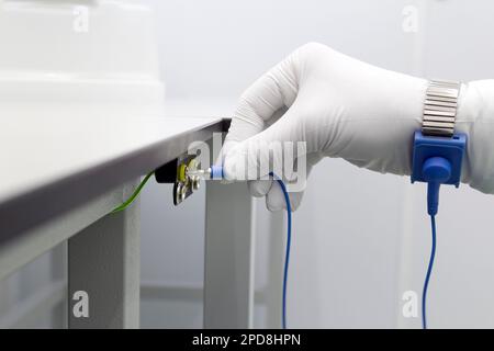Erdungsarmband an der Hand mit ESD-Stoff auf grauem Hintergrund. Antistatisches ESD-Armband oder Erdungsarmband ist ein antistatisches Gerät zur sicheren Stockfoto