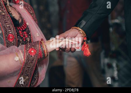 Eine Braut und ein Bräutigam halten an ihrem Hochzeitstag Händchen, die Braut trägt ein wunderschönes weißes Kleid mit Schleier Stockfoto