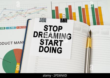 Geschäftskonzept. Auf den Geschäftsdiagrammen liegt ein Stift, ein Notizblock mit Notizzettel mit der Aufschrift „Stop Dreaming Start Do“ Stockfoto