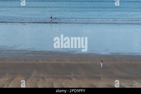 Nicht erkannte Person, die bei Sonnenuntergang am Sandstrand spaziert. Gesunder Lebensstil. Sport im Freien Stockfoto