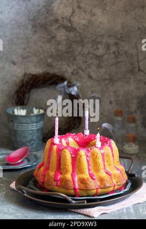 Orangefarbener Vanillekuchen mit pinkfarbenem Glasur, Osterdekor. Stockfoto