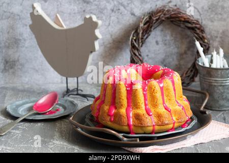 Orangefarbener Vanillekuchen mit pinkfarbenem Glasur, Osterdekor. Stockfoto
