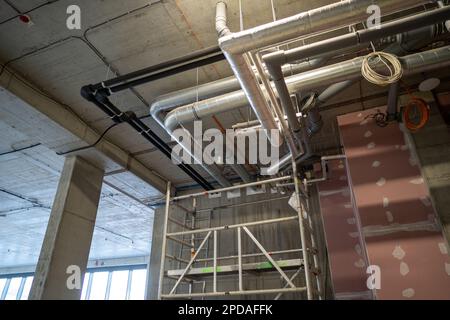 Heizungs- und Kühlsystem des Gebäudes. Neue Rohrinstallation, unter der Decke in der Nähe der Gipskartonwand montiert. Stockfoto