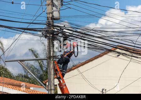 Telekommunikations- und Stromkabel, Techniker, die am Telegrafenmast arbeiten, Gerätewartung, Telegrafenkabel Stockfoto