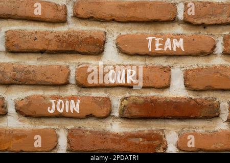 Treten Sie unserem Team Symbol bei. Concept Words Treten Sie unserem Team auf einer roten, braunen Backsteinwand auf einem wunderschönen, rotbraunen Backsteinhintergrund bei. Und werden Sie Teil unseres Teams con Stockfoto