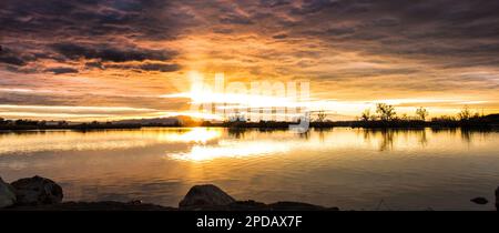 Ein wunderschönes Sonnenuntergangspanorama über einem See Stockfoto