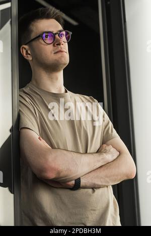 Porträt mit Porträt ein kluger Geschäftsmann mit Brille sitzt am Schreibtisch in einem modernen Büro, schaut in die Kamera, selbstbewusster, zufriedener Freiberufler posiert Stockfoto