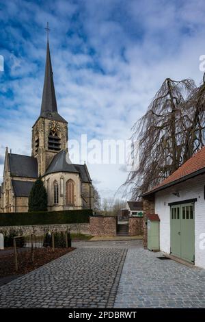 Dilbeek, Flämisch-Brabant, Belgien, 11. März 2023 - Landstraße in Richtung Dorf und Kirche Saint Remigius Stockfoto