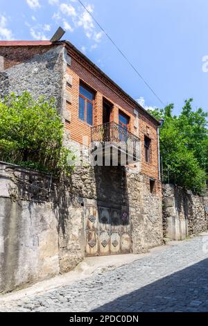 Traditionelles zweistöckiges Wohngebäude in Kutaisi mit gezackten, offenen, dekorativen Balkonen und Türen. Stockfoto