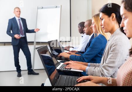 Seitenansicht einer asiatischen Frau, die während eines Geschäftsseminars an einem Notebook arbeitet Stockfoto