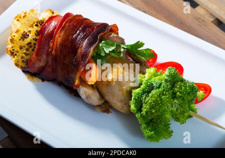 Gegrillte Wachteln im Jamon auf Spieß mit Gemüse Stockfoto