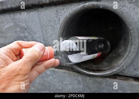 Symbolbild Altglascontainer für Weissglas, Männerhand wirft eine Weinflasche in einen Sammelbehälter Stockfoto