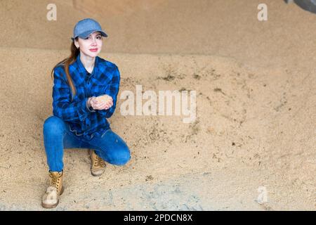 Eine agronomische Frau, die an einem Haufen Sojabohnenschalen hockt Stockfoto