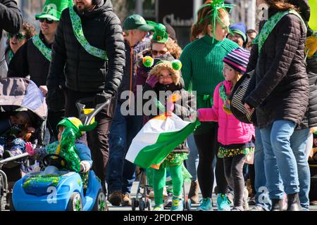 St. Patrick's Day Parade: Grün gekleidete Kinder marschieren entlang der Parade und winken. Halifax, Kanada, März 2023 Stockfoto