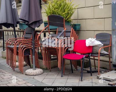 Die Stühle sind übereinander gestapelt. Gartenmöbel. Restaurantrenovierung. Viele verschiedene Stühle. Stockfoto