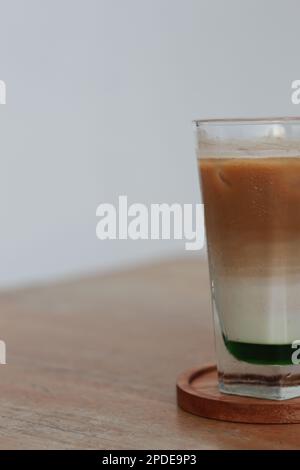 Ein Glas Pandan Coffee Latte, kalt auf dem Tisch serviert. Stockfoto