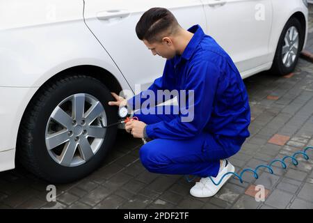 Professioneller Mechaniker, der Reifen beim Autoservice aufpumpt Stockfoto