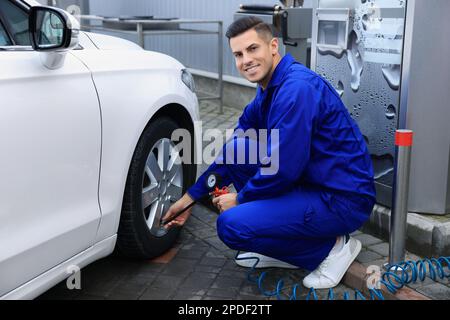 Professioneller Mechaniker, der Reifen beim Autoservice aufpumpt Stockfoto